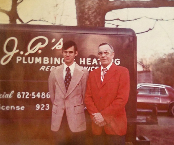 JP wearing a red coat outside of a service truck.